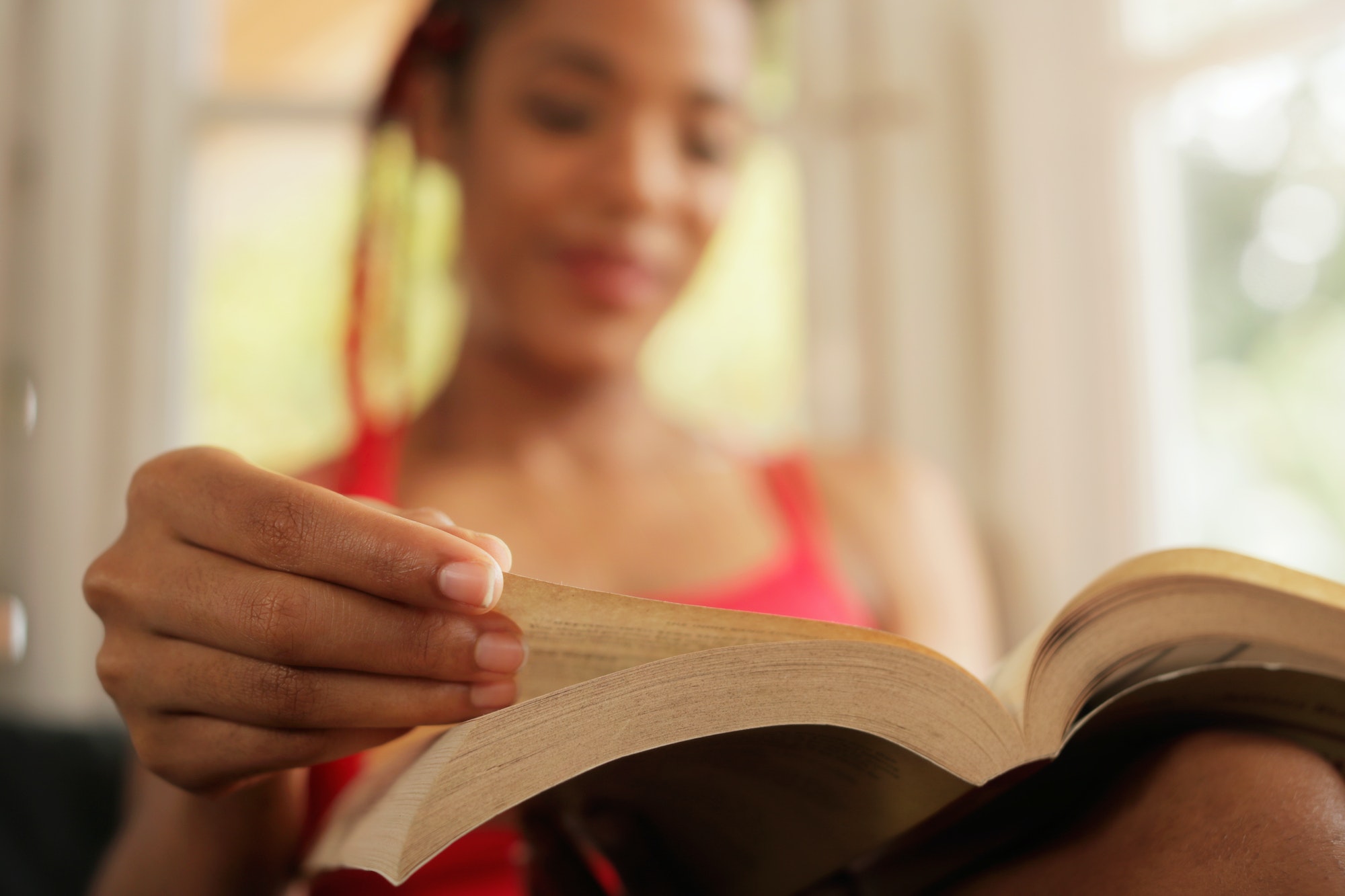 African American Woman Reading Book At Home Focus On Hand