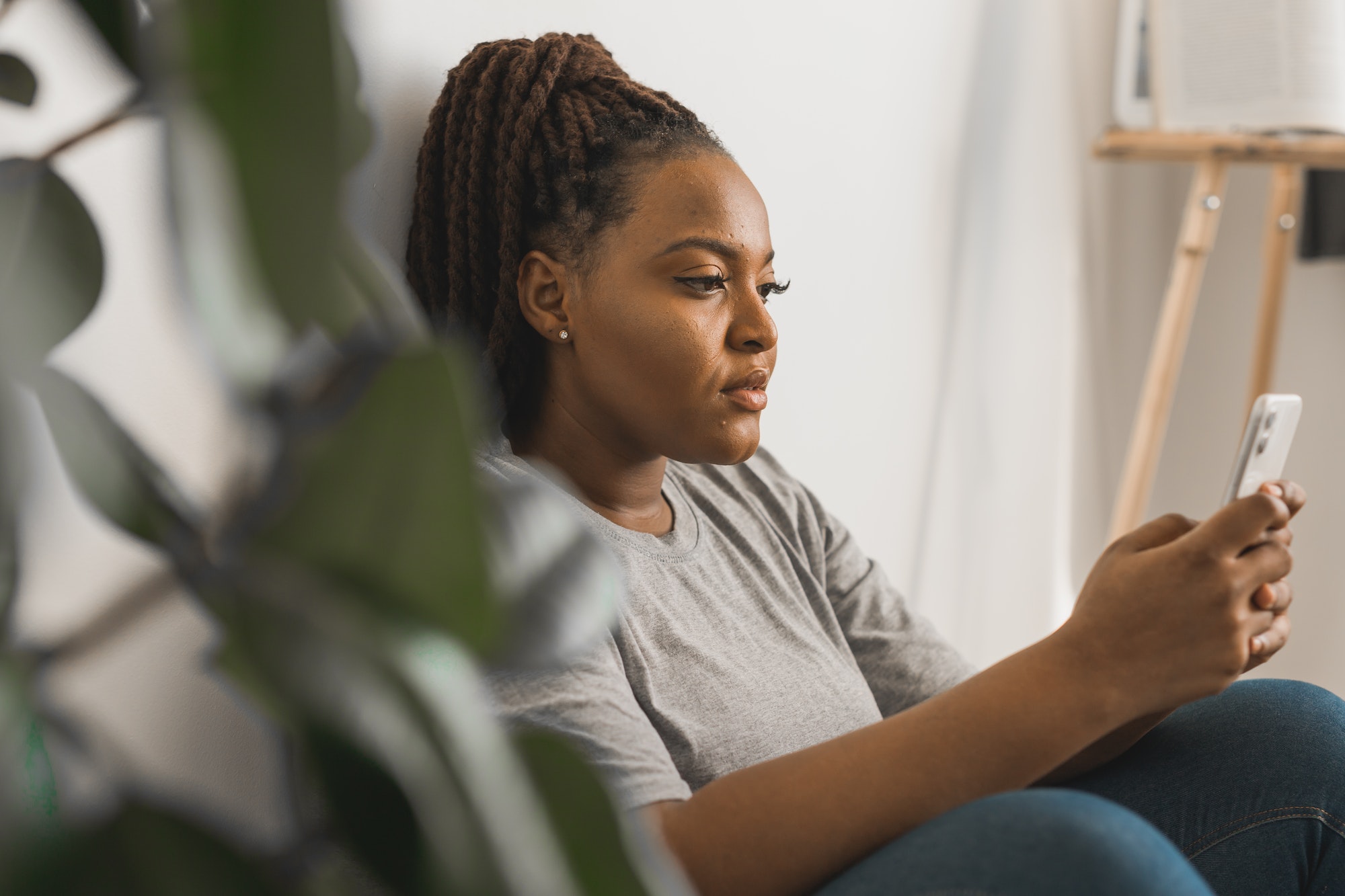 Portrait of African American female student dressed casually holding mobile phone and typing